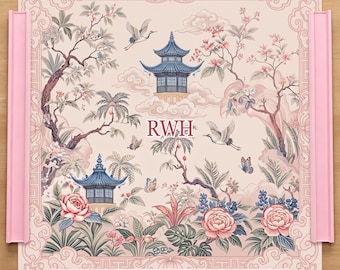 May include: A square puzzle board with a light pink background featuring a printed scene of blue pagodas, flying cranes, butterflies, and pink flowers. The letters RWH are printed in the center. The board has raised pink edges on all four sides.