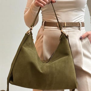 Peut inclure: Sac &agrave; bandouli&egrave;re en daim vert olive avec fermeture &eacute;clair et d&eacute;tails dor&eacute;s. Le sac a une longue bandouli&egrave;re r&eacute;glable et un design souple. Un accessoire &eacute;l&eacute;gant pour un usage quotidien.