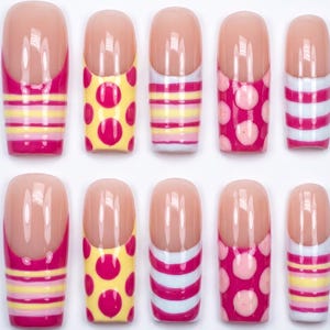 May include: A set of ten press-on nails featuring a French manicure style with a nude base and various colorful patterns on the tips, including horizontal stripes in pink, yellow, and white, as well as pink polka dots on yellow or pink backgrounds.