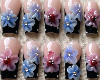 Unghie finte 3D con coccinella e fiori, french manicure nera, nail art floreale.