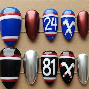 May include: A collection of handcrafted nails with diverse designs. Some nails are blue with white and red stripes, others are metallic red or silver. Two nails display the number 24, and two display the number 81. The text "HANDCRAFTED NAILS" is at the top.