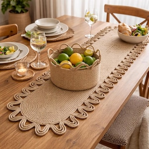 May include: A dining table set with a woven jute table runner and a basket filled with lemons and limes. The table is set with plates, glasses, and a bowl of salad. A lit candle sits on a coaster.
