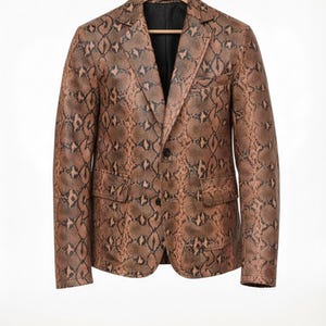 May include: A brown and black snakeskin-patterned blazer with a notched lapel, two front pockets, and a two-button closure. The jacket is hanging on a wooden hanger against a white background. The lining is black.