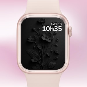 Op de afbeelding: Een roségouden smartwatch met een lichtroze band. De wijzerplaat toont een zwart bloemenontwerp, de tijd 10:35 en de datum ZAT 18 in het wit. Het horloge heeft een digitaal display en een zijkantknop.