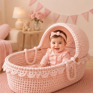 May include: A light pink crocheted baby bassinet with a scalloped edge and integrated handles, featuring a rounded hood. The bassinet is constructed from thick yarn in a textured stitch pattern, providing a soft and structured enclosure for an infant.