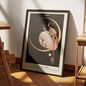 Pode incluir: Impressão artística emoldurada com uma mulher sentada em uma lua crescente dourada. A obra de arte, rotulada como "THE MOON", tem um fundo escuro com o numeral romano XVIII no topo. A mulher está vestida com um vestido detalhado em estilo vintage.