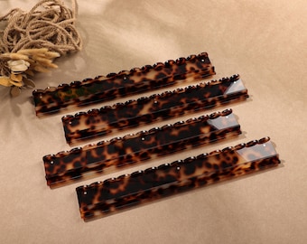 May include: Four rectangular hair combs featuring a brown and black tortoiseshell pattern. Each comb has a scalloped top edge and a series of fine teeth along the bottom. The combs are arranged in a parallel formation, showcasing the glossy finish.