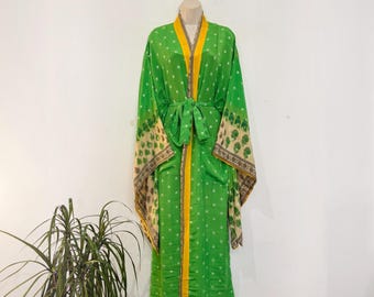 May include: A long-sleeved green robe featuring a white polka dot pattern, a bright yellow trim along the front opening, and wide sleeves with a cream-colored border decorated with a repeating green leaf print, tied at the waist with a sash.
