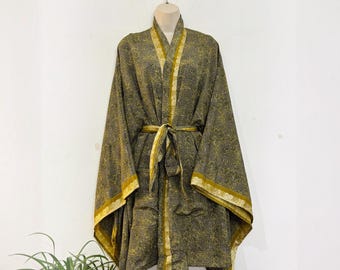 May include: A long-sleeved kimono robe featuring a dark charcoal gray base with an intricate, repeating gold and yellow floral pattern. The garment includes a solid gold-colored trim along the front opening, sleeve cuffs, and a matching tie belt.