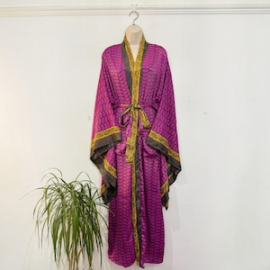 Peut inclure: Un long peignoir de style kimono magenta avec un motif répétitif de gouttes sombres. Le vêtement présente une bordure contrastée à motifs jaunes et verts le long de l'ouverture avant, des poignets et de l'ourlet, avec une ceinture assortie.