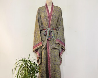 May include: A long-sleeved kimono robe featuring an intricate paisley pattern in shades of olive green, purple, and gold. The garment includes a matching fabric tie belt at the waist and a contrasting border along the front opening and cuffs.