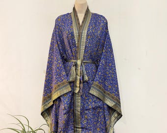 May include: A long-sleeved kimono-style robe in a vibrant blue fabric featuring an intricate gold and yellow floral pattern. The garment includes a matching tie belt at the waist and wide, structured lapels with a metallic gold border trim.