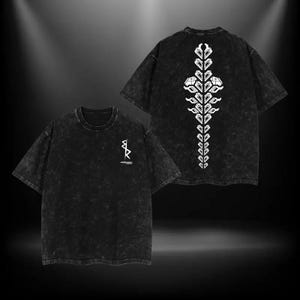May include: Two black t-shirts with a white graphic design. One shirt has a small design on the front, and the other has a larger, vertical design on the back. The shirts have a faded, textured appearance.