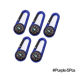 May include: Five blue carabiner compasses with black and white details. Each compass has a black dial with directional markings and a needle. The carabiners are a vibrant blue color. The text "#Purple-5Pcs" is in the bottom right corner.