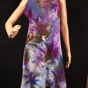 May include: A sleeveless, knee-length dress with a vibrant tie-dye pattern. The dress features a mix of colors, including purple, blue, pink, and green, creating a watercolor effect. The dress has thin straps and a slightly flared skirt, offering a casual and artistic look.