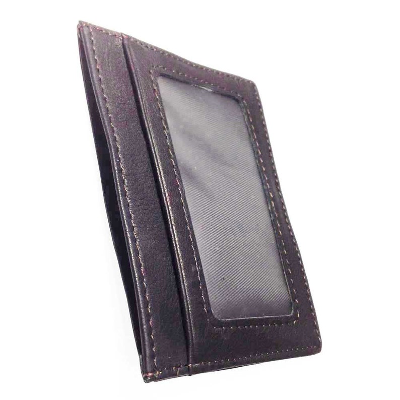 May include: A dark brown leather cardholder with a clear plastic window. The cardholder has a slim design with visible stitching around the edges. The interior is lined with a textured fabric.