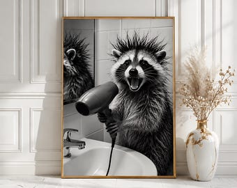 May include: A black and white framed wall art print featuring a raccoon with spiky, wet fur standing in front of a bathroom mirror and sink, holding a handheld hair dryer. The raccoon has an open mouth and is looking directly forward.