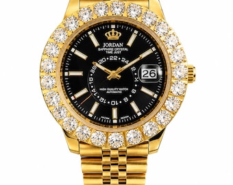 May include: A gold-tone wristwatch with a black dial, featuring a bezel encrusted with clear round stones. The dial displays the text JORDAN, SAPPHIRE CRYSTAL, TIME JUST, and HIGH QUALITY WATCH AUTOMATIC, with a date window showing 26.