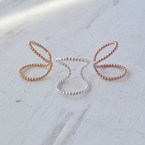 May include: Three delicate rings made of small beads. The rings are in gold, rose gold, and silver.