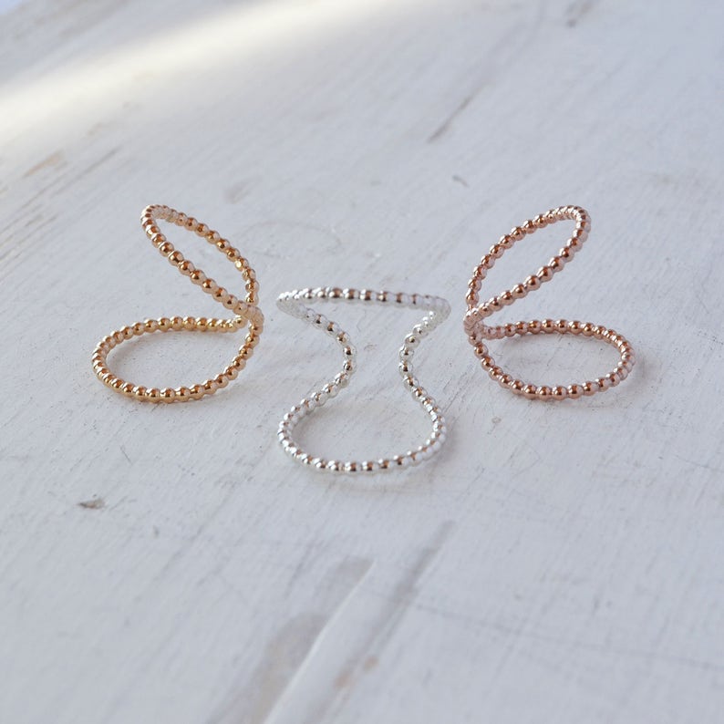 May include: Three delicate rings made of small beads. The rings are in gold, rose gold, and silver.