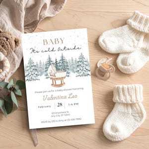 May include: A baby shower invitation with the text "BABY It's cold Outside" and details for Valentina Leo's shower. The image includes baby socks, a pacifier, and a wooden toy, all on a light wood surface.