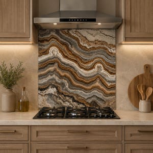 May include: A kitchen backsplash panel featuring a natural stone pattern with swirling layers of brown, tan, white, and charcoal gray. The rectangular panel is positioned behind a black gas stovetop and beneath a stainless steel range hood.
