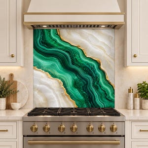 May include: A kitchen backsplash panel featuring a vibrant green and white marbled pattern with flowing, wavy lines and thin gold accents. The design mimics the appearance of natural stone, positioned directly behind a stainless steel gas stove.