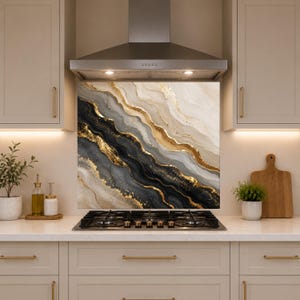 May include: A square kitchen backsplash panel featuring an abstract design of flowing, wavy layers in shades of black, charcoal, cream, and beige, accented with shimmering gold metallic veins that create a marbled, geode-like appearance.