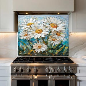 May include: A mosaic splashback depicting white daisies with yellow centres set against a blue and green backdrop. The mosaic is positioned above a stainless steel gas range in a contemporary kitchen.