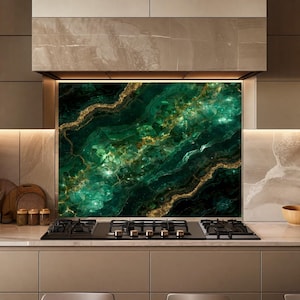 May include: A rectangular kitchen backsplash panel featuring a deep emerald green marble pattern with prominent gold veining. The surface displays a glossy, crystalline texture with light reflecting off the dark green and metallic gold swirls.