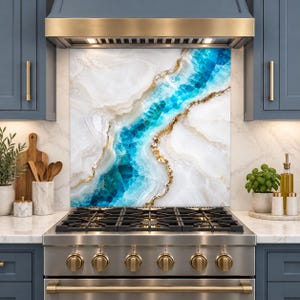 May include: A kitchen backsplash panel featuring a white and blue agate-inspired pattern with gold-toned veining. The rectangular panel is positioned behind a stainless steel gas range with six burners and metallic knobs, set between blue cabinets.