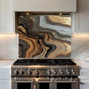 May include: A decorative kitchen backsplash with a swirling abstract design. The artwork features a blend of gold, brown, black, and gray tones, creating a marbled effect. The backsplash is installed above a stainless steel gas range.