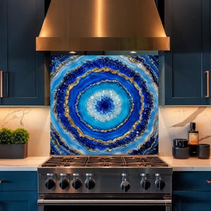 May include: A square kitchen backsplash panel featuring a vibrant blue and white agate stone pattern with concentric rings and metallic gold accents. The design displays a crystalline center surrounded by layered bands of deep navy and bright cyan.