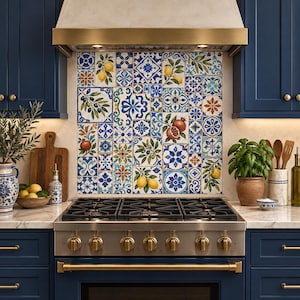 May include: A kitchen backsplash featuring a mosaic of square tiles with blue, white, and yellow patterns, including illustrations of lemons, olives, and pomegranates, positioned above a stainless steel gas range with six burners and gold knobs.