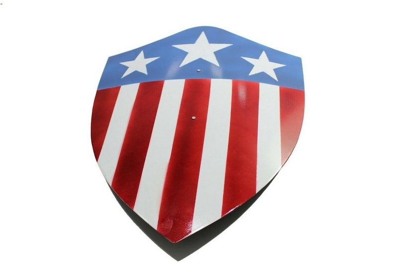 Op de afbeelding: Een schildvormig object met een patriottisch ontwerp. Het bovenste gedeelte is blauw met drie witte sterren, terwijl het onderste gedeelte afwisselend rode en witte strepen heeft. Het schild heeft een glanzende afwerking en een puntige onderkant.