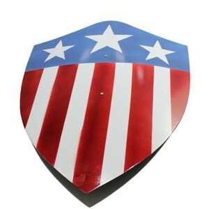 Op de afbeelding: Een schildvormig object met een patriottisch ontwerp. Het bovenste gedeelte is blauw met drie witte sterren, terwijl het onderste gedeelte afwisselend rode en witte strepen heeft. Het schild heeft een glanzende afwerking en een puntige onderkant.