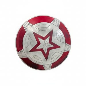 May include: A round shield with a red and silver design. The outer rim is red, and the center features a large red star within a silver circle. The shield has a metallic appearance.