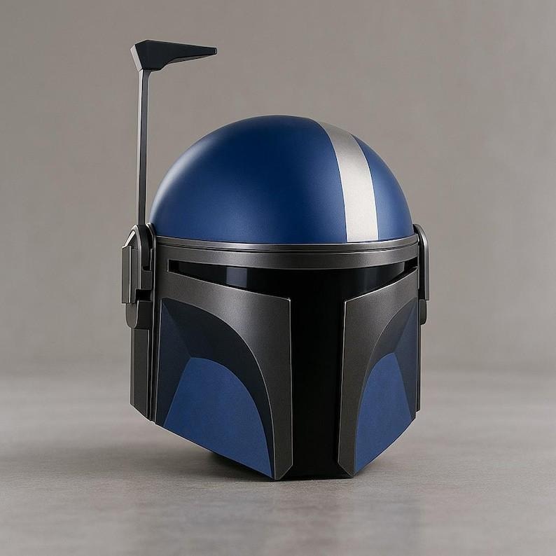May include: A blue and silver helmet with a distinctive design. The helmet features a blue dome with a silver stripe down the center and a black visor. A vertical antenna extends from the top. The helmet is likely a costume or collectible item.