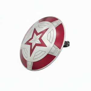May include: A silver and red shield with a white star in the center. The shield has a circular shape with red and silver segments. A black strap is attached to the back of the shield.