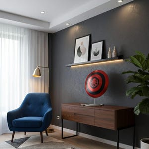 May include: Interior design featuring a blue armchair, a wooden cabinet, and a geometric rug. A red and black shield decorates the cabinet. Artwork and a shelf with bottles are on the dark gray wall.