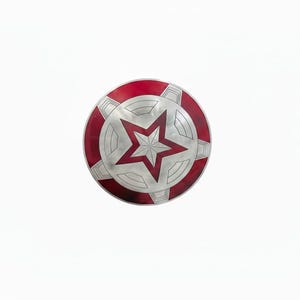 May include: A round, red, white, and silver shield with a central red star design. The shield has a red outer ring and a silver star in the center, with silver geometric shapes around the star.