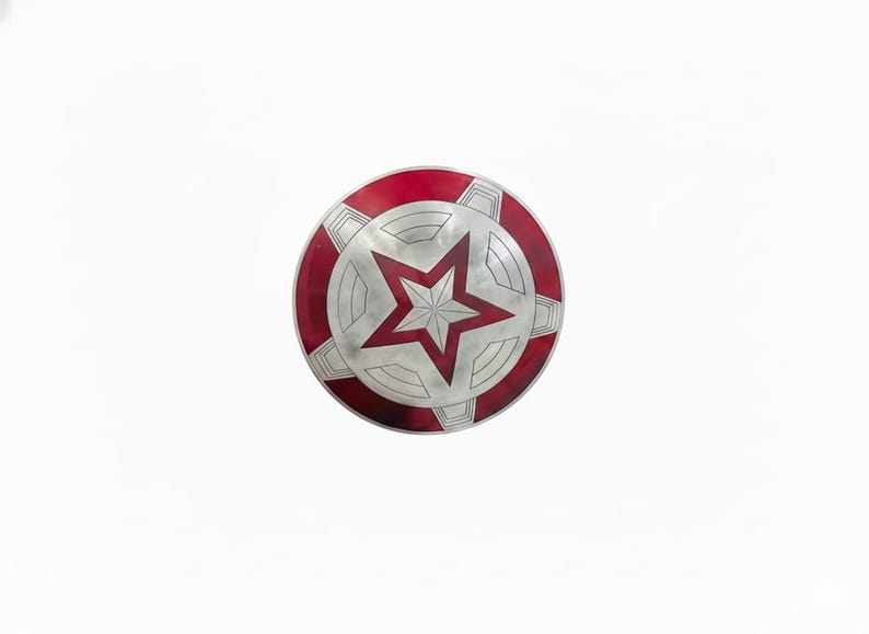 May include: A round, red, white, and silver shield with a central red star design. The shield has a red outer ring and a silver star in the center, with silver geometric shapes around the star.
