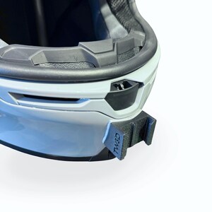 Peut inclure: Gros plan d'un casque de moto blanc avec un int&eacute;rieur noir et un support de montage noir. Le support porte l'inscription "TW3D".