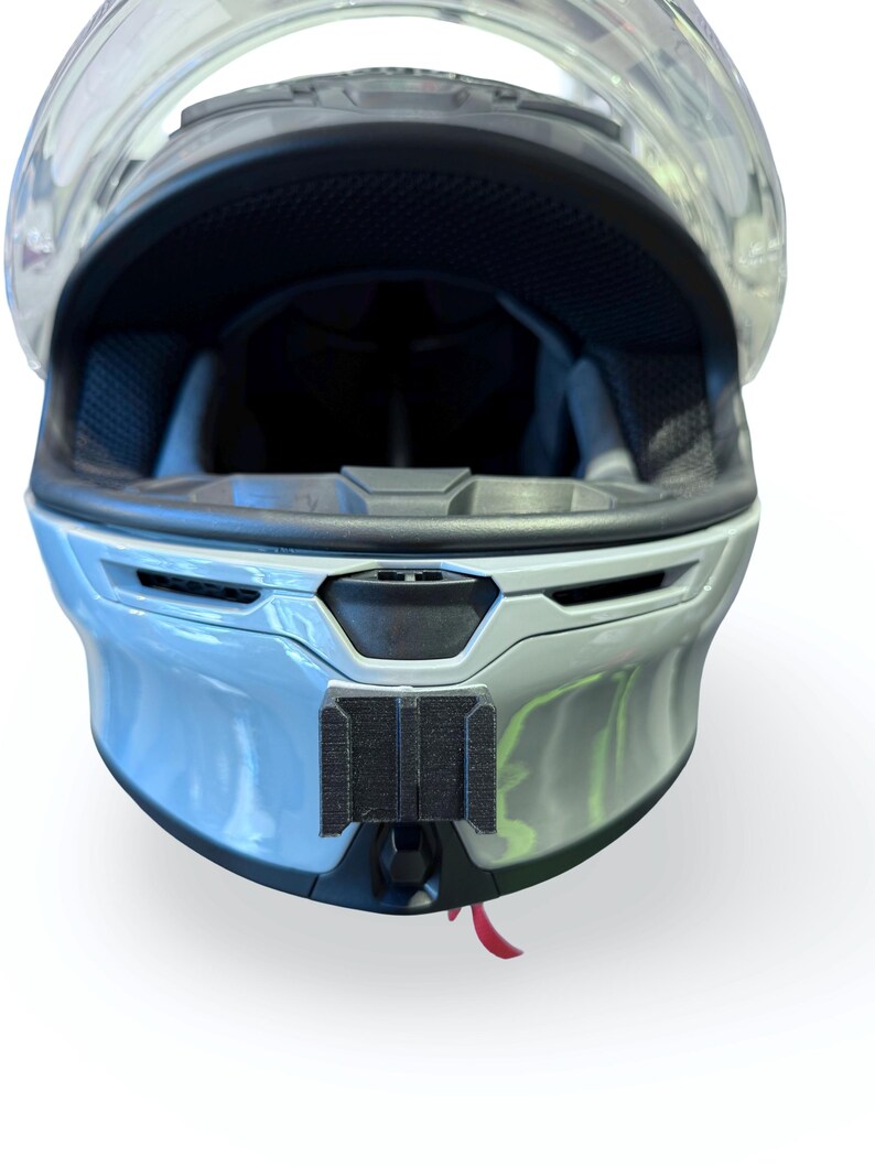 Peut inclure: Casque de moto bleu clair avec une visi&egrave;re transparente. L'int&eacute;rieur du casque est noir et il y a un support de montage noir &agrave; l'avant. Une petite languette rouge pend en bas.
