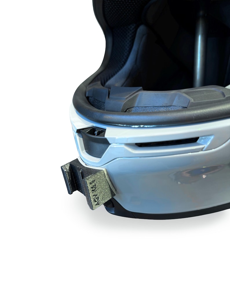 Peut inclure: Gros plan sur un casque blanc et noir avec un accessoire noir fix&eacute; sur le c&ocirc;t&eacute;. L'accessoire porte l'inscription "ASV RACE". Le casque est con&ccedil;u pour la s&eacute;curit&eacute; et la protection.