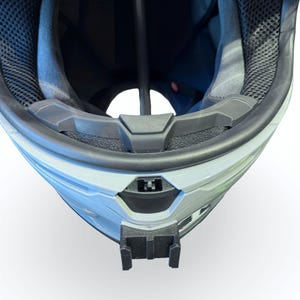 Peut inclure: Gros plan d'un casque blanc et gris avec un int&eacute;rieur noir. Le casque est &eacute;quip&eacute; d'une jugulaire noire et d'un support noir &agrave; l'avant. L'int&eacute;rieur pr&eacute;sente une maille noire et un rembourrage gris.