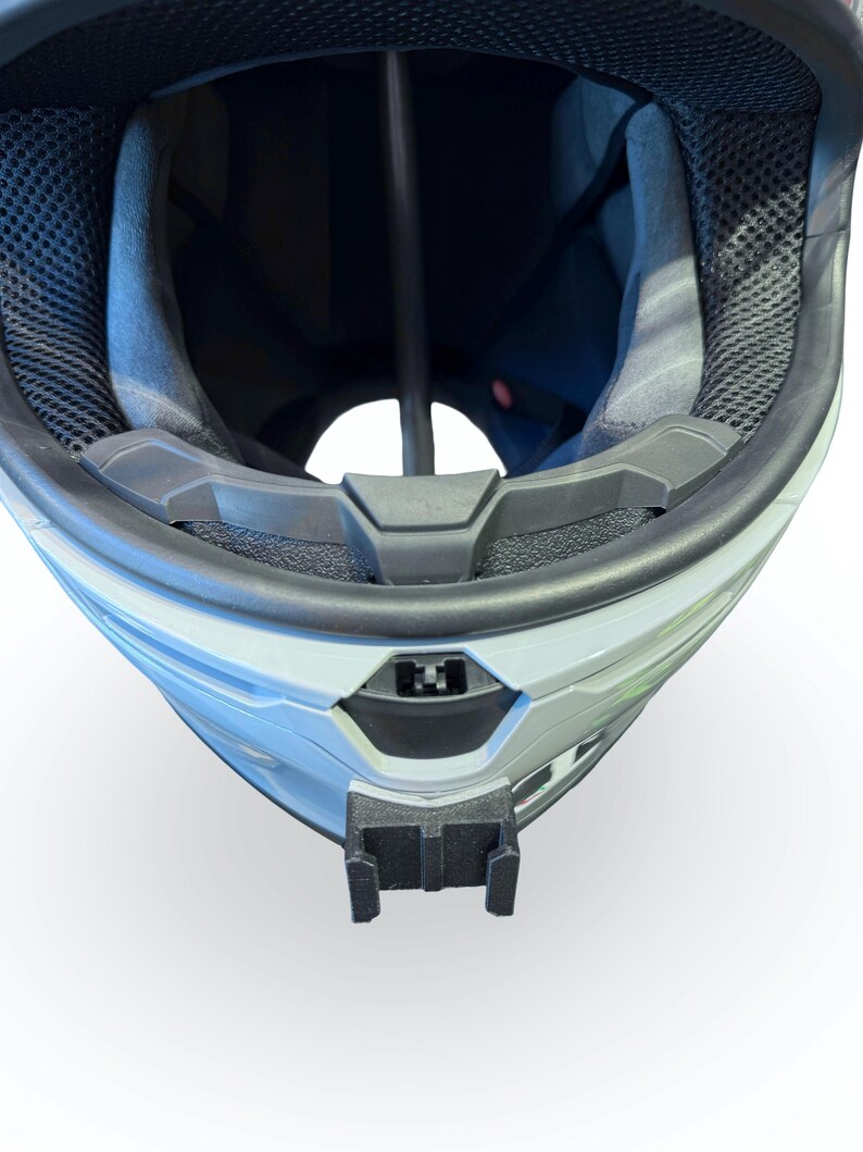 Peut inclure: Gros plan d'un casque blanc et gris avec un int&eacute;rieur noir. Le casque est &eacute;quip&eacute; d'une jugulaire noire et d'un support noir &agrave; l'avant. L'int&eacute;rieur pr&eacute;sente une maille noire et un rembourrage gris.