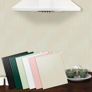Pode incluir: Uma coleção de seis azulejos decorativos quadrados e canelados em várias cores: preto, verde escuro, verde claro, branco, rosa e bege. Os azulejos estão dispostos em forma de leque, com uma exaustor branco e uma parede creme com linhas verticais no fundo.