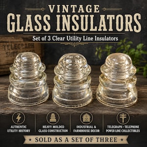 Op de afbeelding: Een set van drie doorzichtige glazen isolatoren voor nutsleidingen met een zware gegoten constructie. Elk stuk heeft een afgeronde bovenkant en een getrapte basis. De tekst VINTAGE GLASS INSULATORS Set of 3 Clear Utility Line Insulators is zichtbaar.