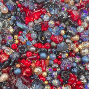 May include: A large collection of loose craft beads in various shapes, sizes, and textures. The assortment includes red, blue, black, and metallic gold beads, featuring flower, butterfly, round, and faceted designs with glossy and matte finishes.